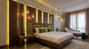 Master bedroom with wood panels, green bed, and chaise lounge at Globe Residency Karachi
